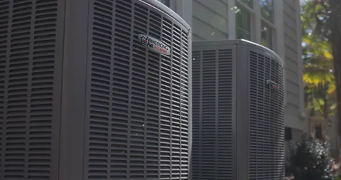 A row of outdoor central air conditioning condensers beside a home