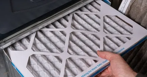 A hand sliding a pleated air filter into place