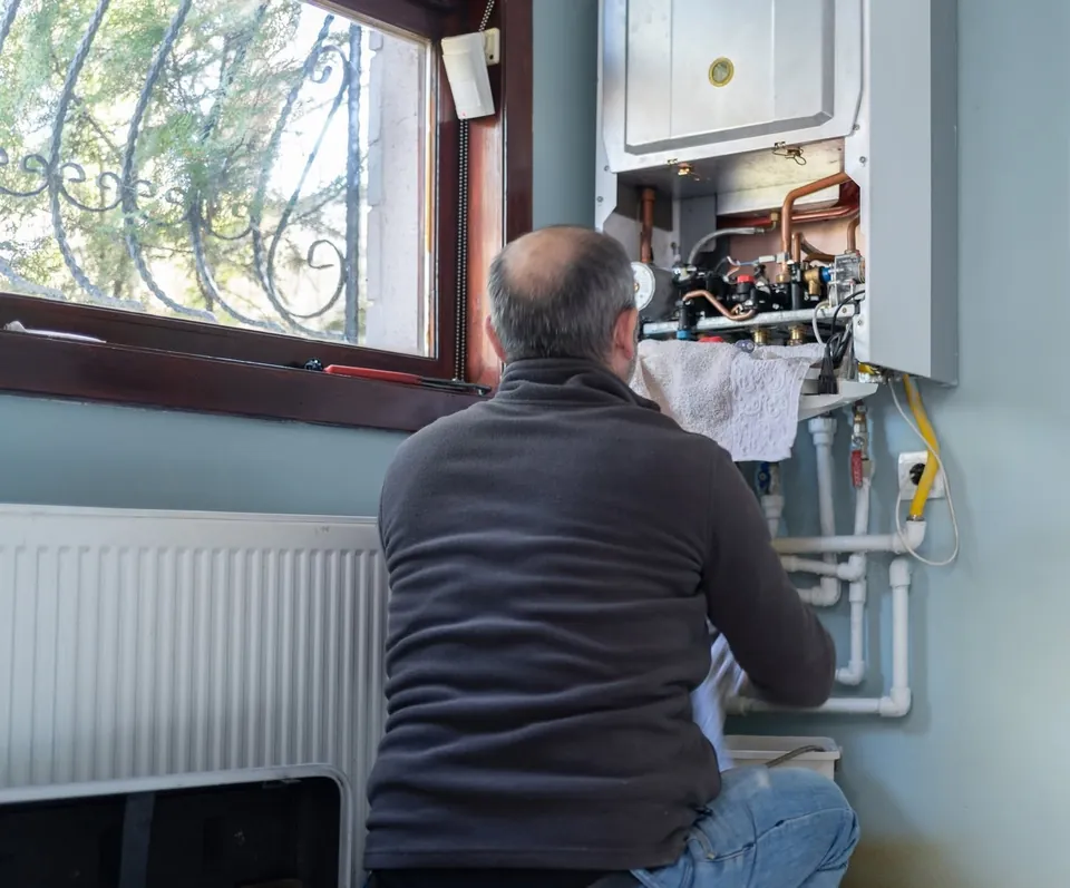 A Fesmire technician servicing a wall-mounted heating unit in a customer’s home