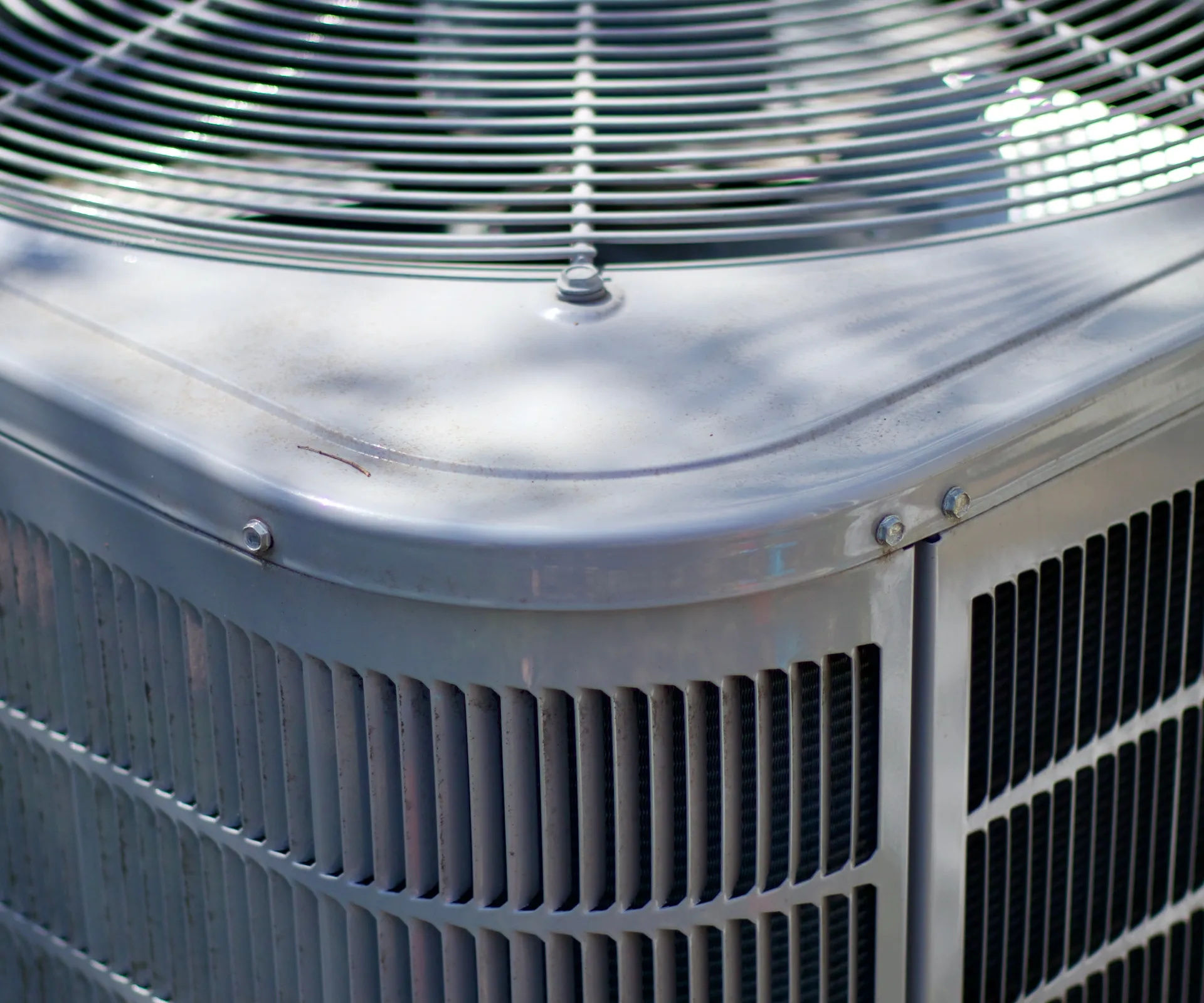 Close-up of an outdoor heat pump’s fan grille and coil guard