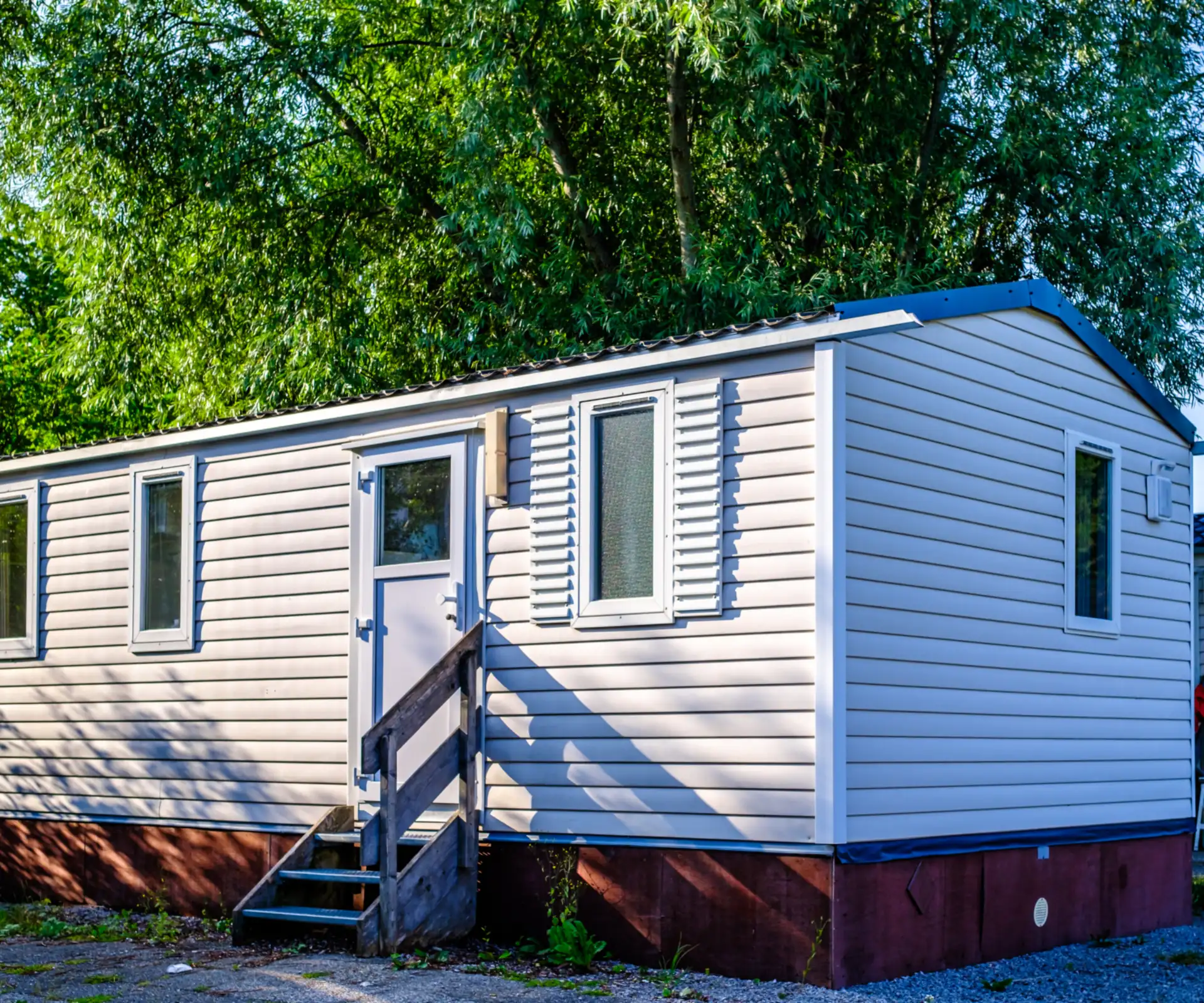 A white manufactured home with entry steps on a sunny lot
