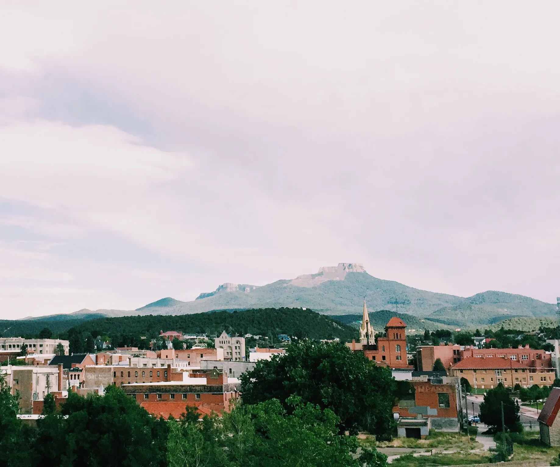 Pueblo, Colorado’s downtown rooftops and trees beneath the mountains